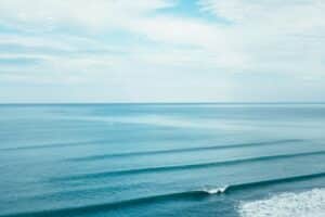 Calm blue ocean landscape with gentle waves under a partly cloudy sky.