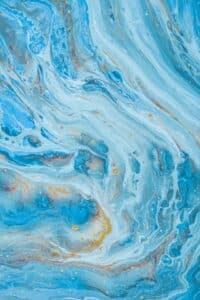 Blue and white fluid abstract art with swirls and speckles.