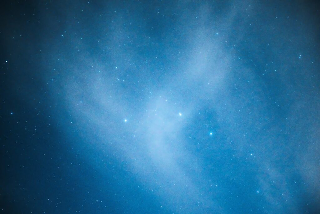 Starry night sky with wispy clouds and bright stars.