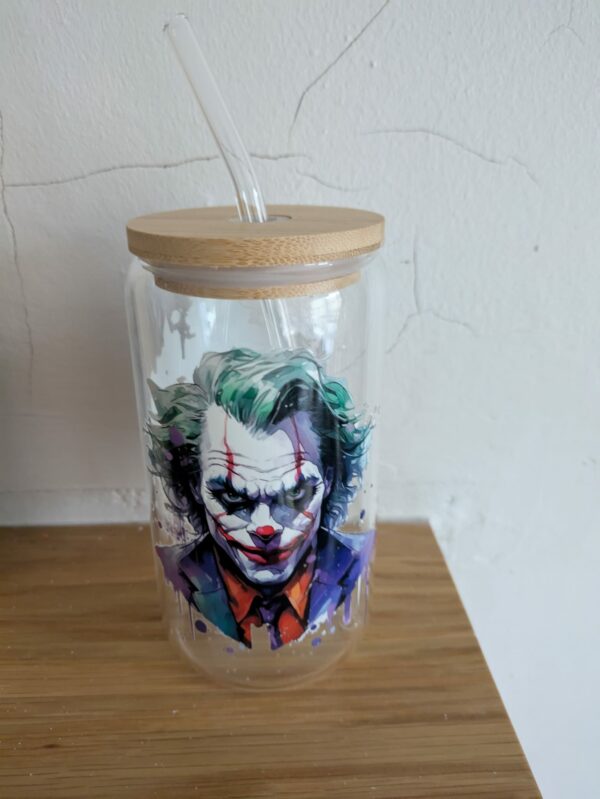 Glass jar with a bamboo lid and straw, featuring colorful art of a clown face.