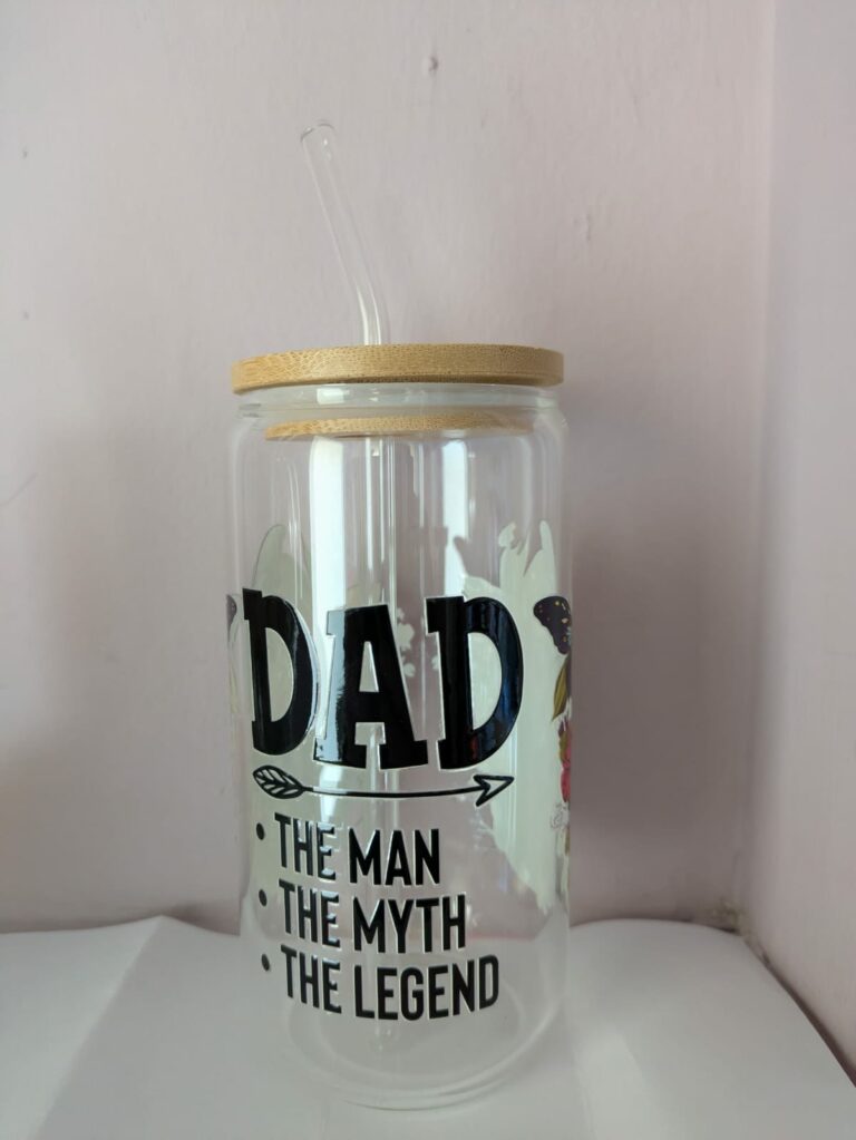 Glass tumbler with straw, wood lid, and text: "Dad, The Man, The Myth, The Legend" on a light background.