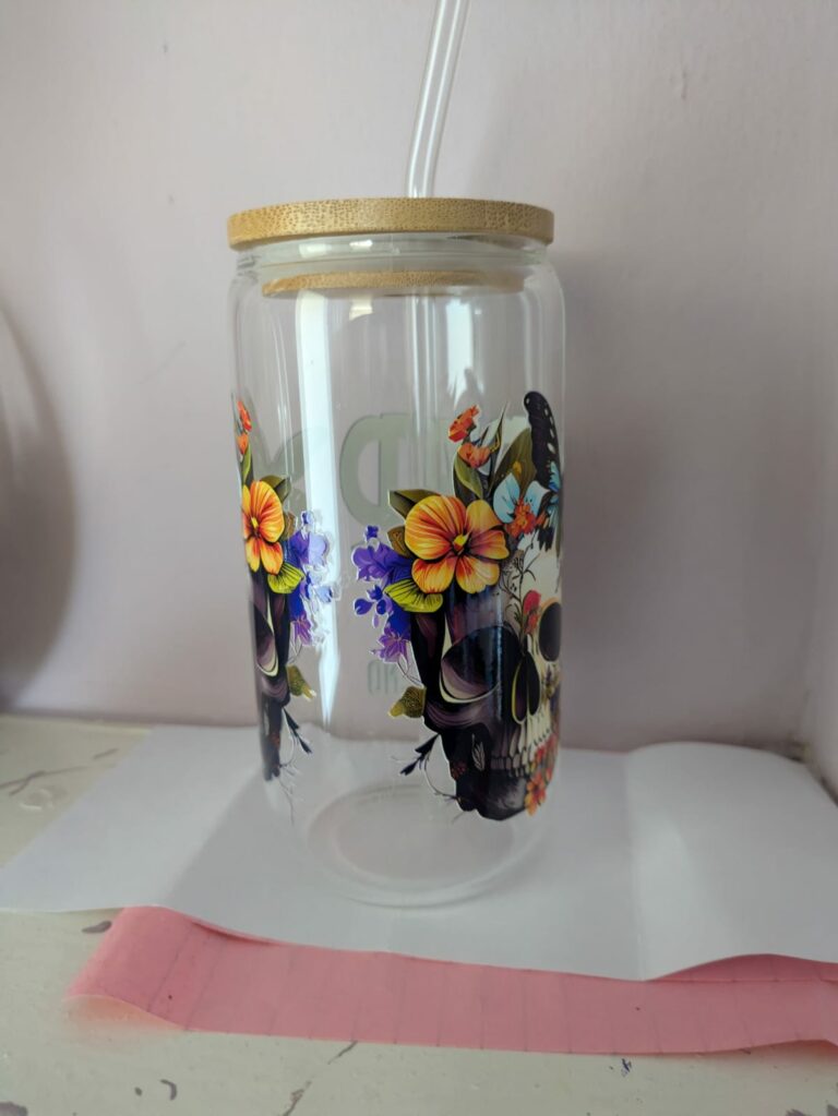 Glass skull mug with floral design, bamboo lid, and straw.
