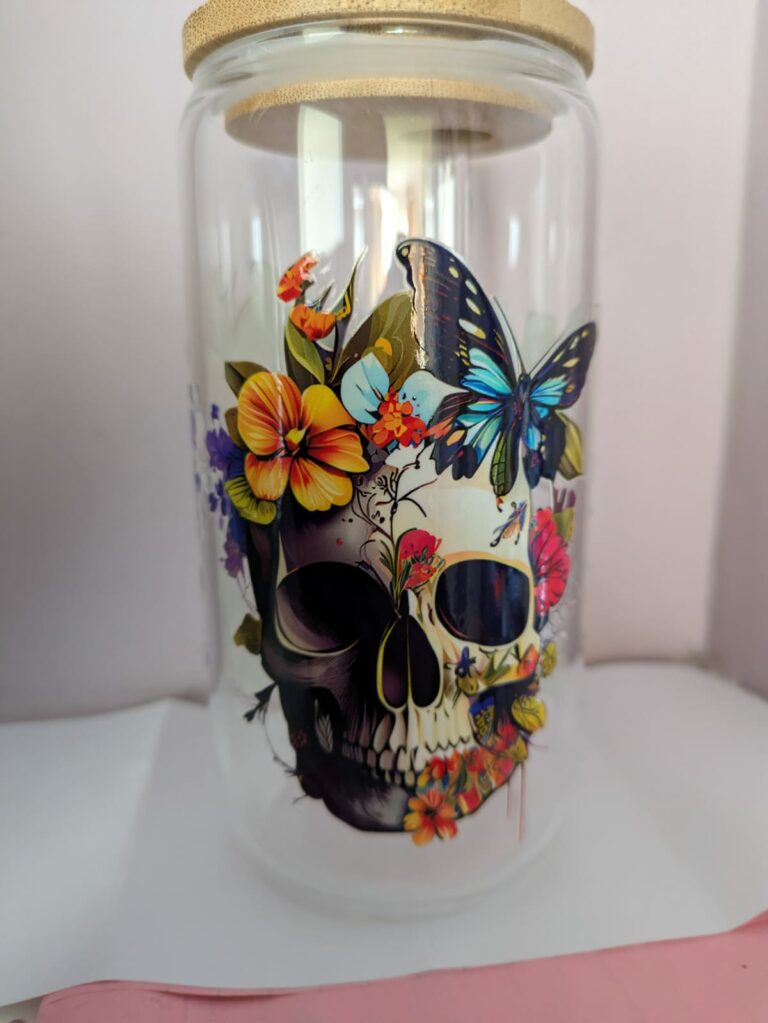 Glass jar with colorful skull, flowers, and butterflies design, featuring a wooden lid.