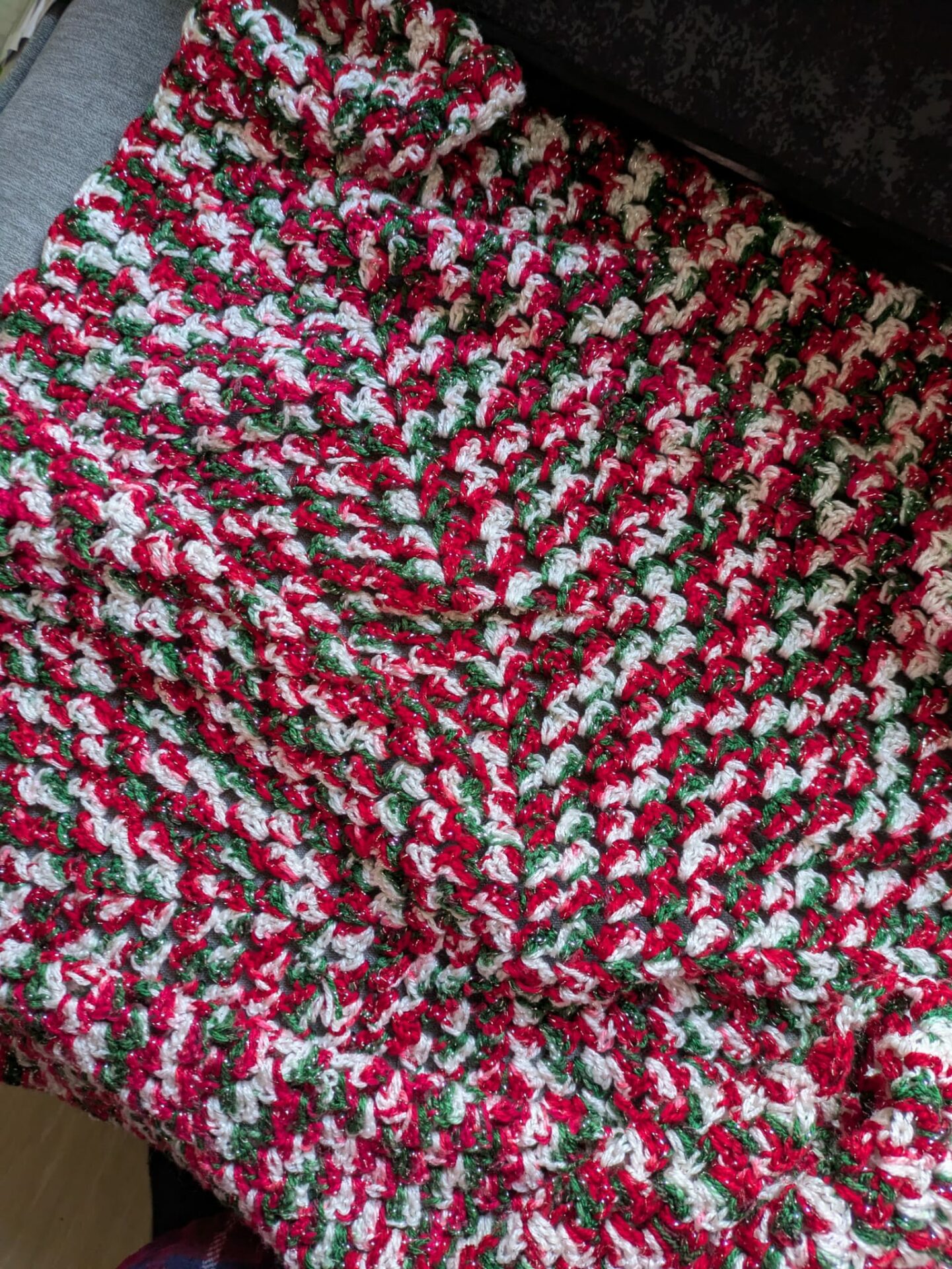 Colorful crochet blanket with red, green, and white threads.